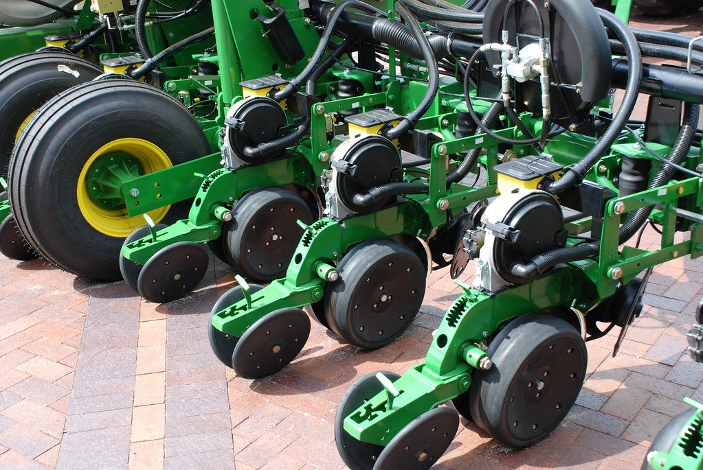A powerful modern tractor mowing fields in a lush, sunny countryside, showcasing agricultural machinery at work.